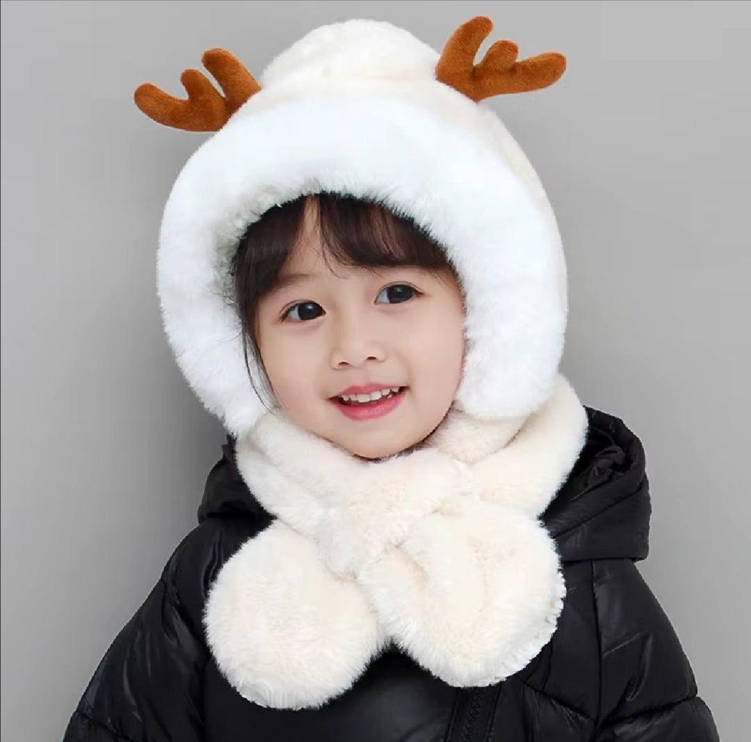 Child wearing a white hood with reindeer antlers and a matching scarf on a gray background